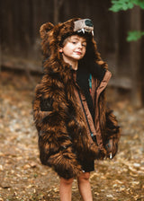 Child wearing a bear costume in a forest setting