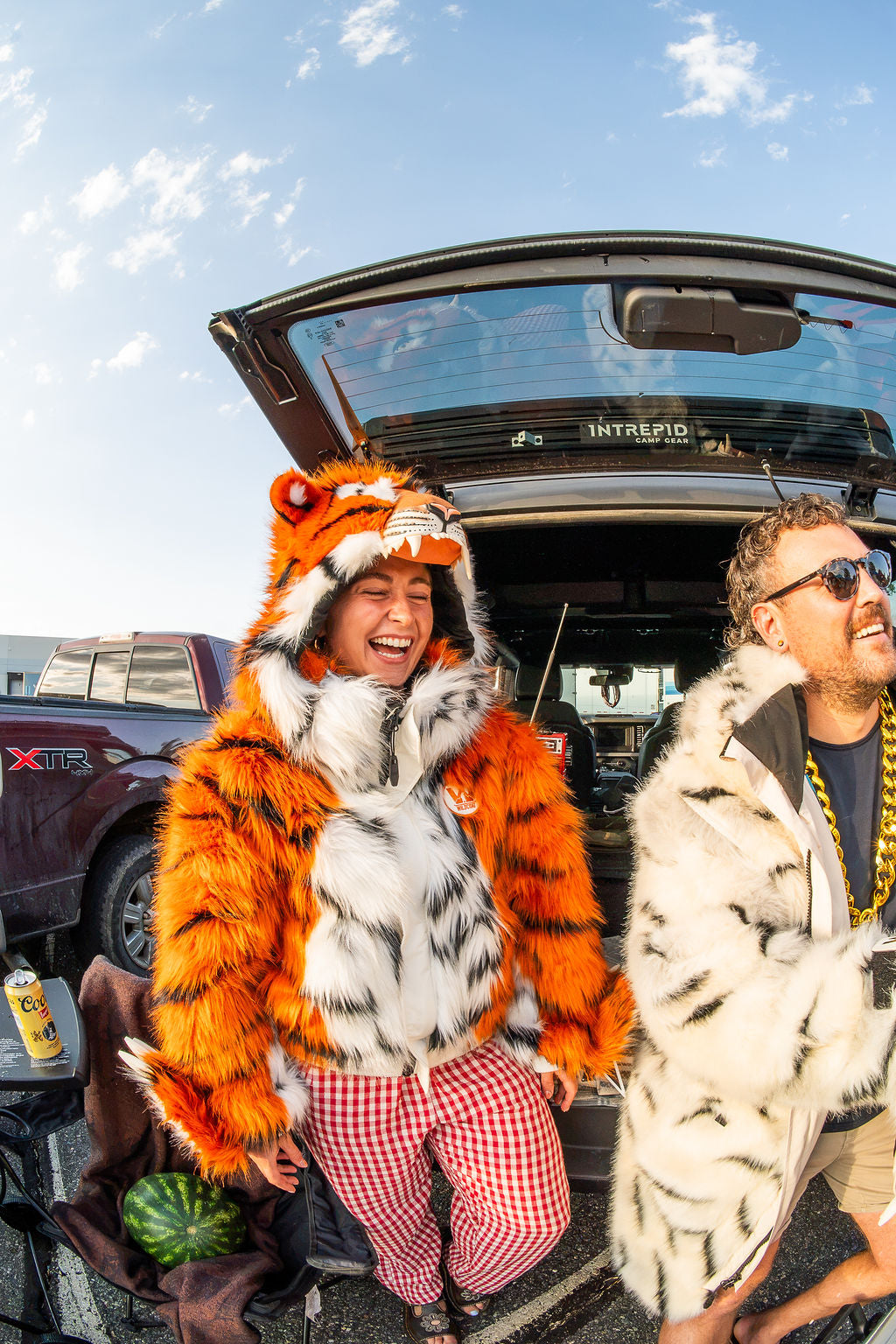 Woman Cincinnati Bengals fan wearing the wildcoat orange bengal tiger bomber at a tailgate next to a man wearing the wildcoat white bengal tiger parka