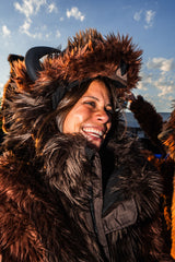 A girl smiling while wearing a wildcoat brown buffalo coat at a tailgate party