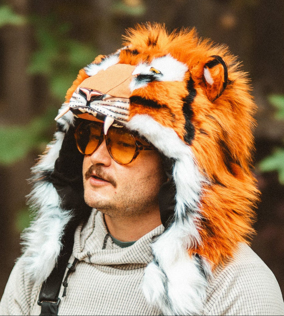 Person wearing a tiger-themed hood, or helmet cover, with a forest background