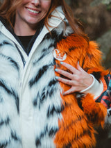 A close-up lifestyle shot of the wildcoat orange tiger bomber coat, showcasing the embroidered chest patch with W wildcoat logo. The coat is a faux fur tiger patterned winter wear, winter coat garment.