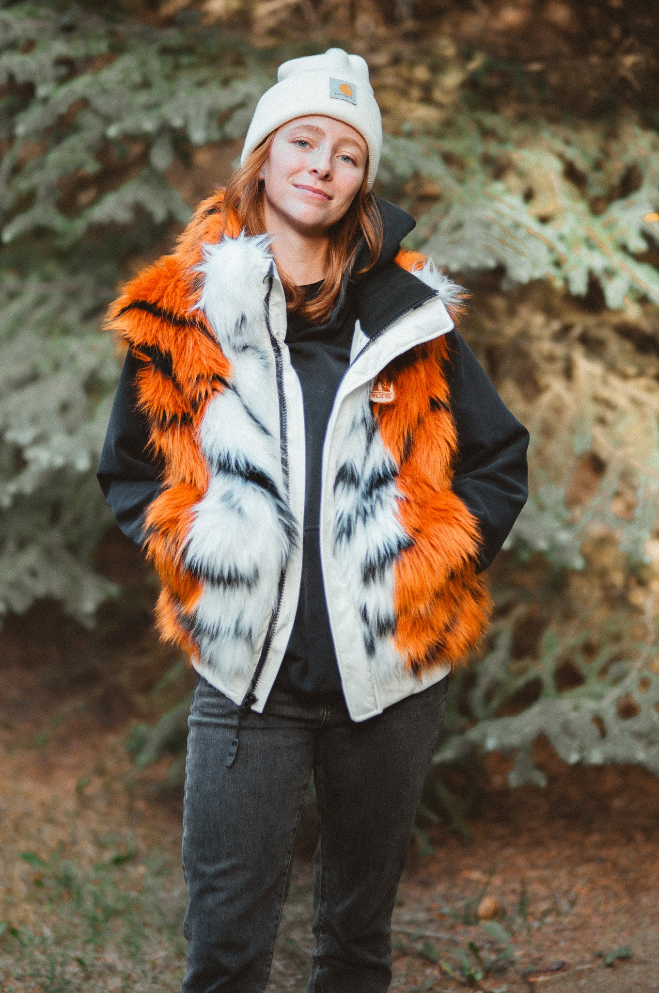 A woman wearing the wildcoat orange tiger bomber coat, a plush tiger patterned, costume, faux fur, winter coat. She has the sleeves and hood detached turning it into a vest.
