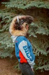 Woman wearing the wildcoat great white buffalo hood showing the full side profile, including bone-colored horn and bright blue eye