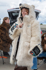 woman wearing a faux fur polar bear parka at a bears tailgate, showing off the crested emblem on the chest with her paws flipped up