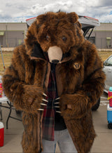 man wearing a faux fur grizzly bear parka coat at a chicago bears tailgate, looking down to show the full bear hood