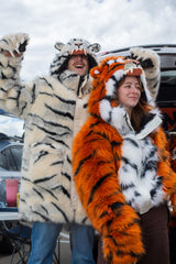 woman wearing a wildcoat faux fur orange bengal tiger bomber-cut coat / jacket. man on her left is wearing a white bengal tiger parka length faux fur coat 