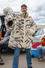 man wearing a wildcoat faux fur white bengal tiger coat, the hood is zipped off and hes holding it up to the camera in his right hand