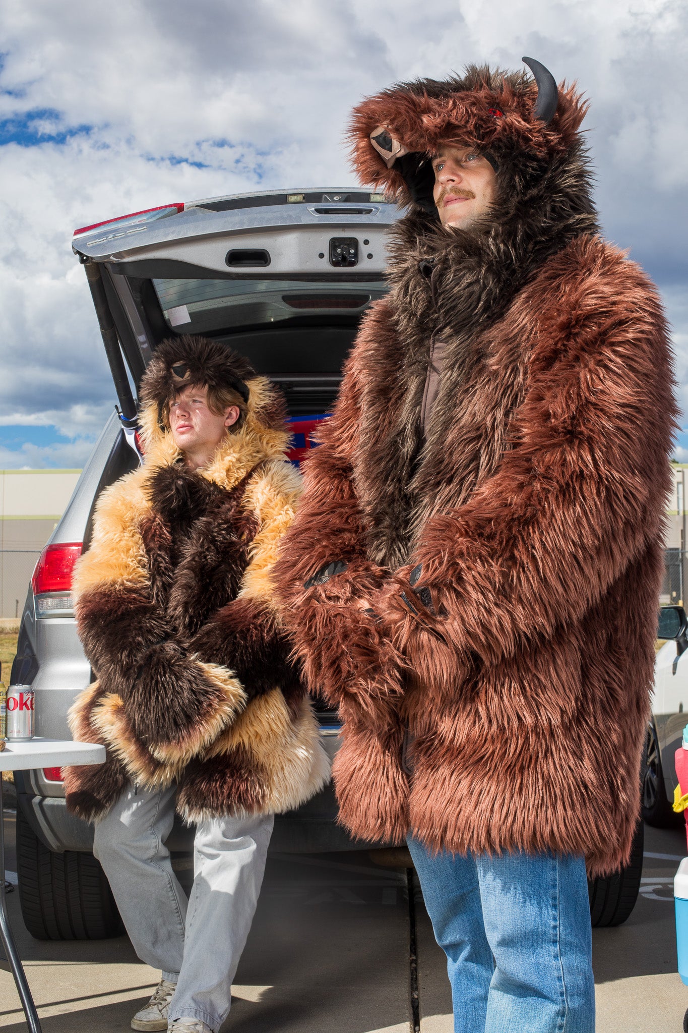 man wearing a wildcoat v6 buffalo bison faux fur winter coat at a tailgate with a man in the background wearing the great white buffalo coat