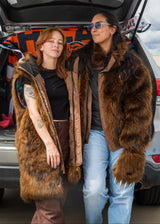 Two women wearing wildcoat faux fur grizzly bear parka coats at a bears tailgate. The woman on the left is wearing her coat with the sleeves and hood detached, the girl on the right is wearing a bomber-style waist cut version with the hood detached.